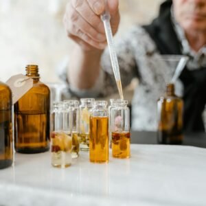 A person blends aromatic essences using a dropper for bespoke fragrances, emphasizing artisanal craftsmanship.