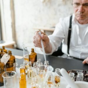 Senior male preparing natural fragrance mixtures indoors using lab tools.