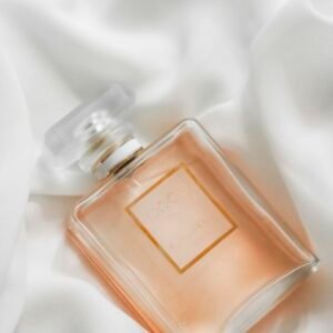 Stylish perfume bottle resting on smooth white fabric background.