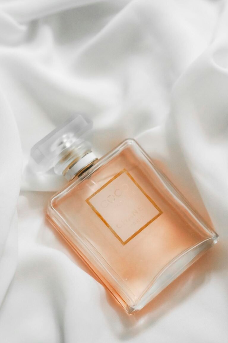 Stylish perfume bottle resting on smooth white fabric background.