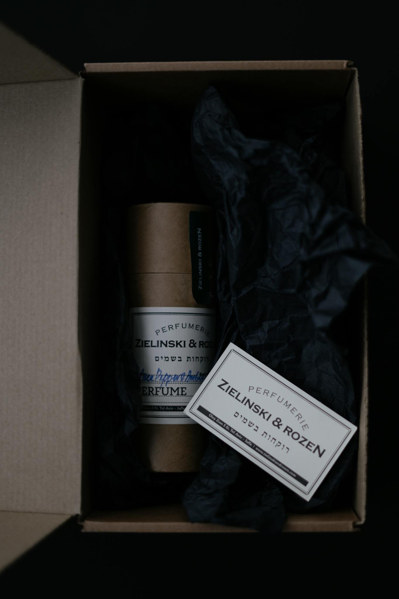 Top view of perfume packaging with elegant design in a carton box and dark aesthetic.